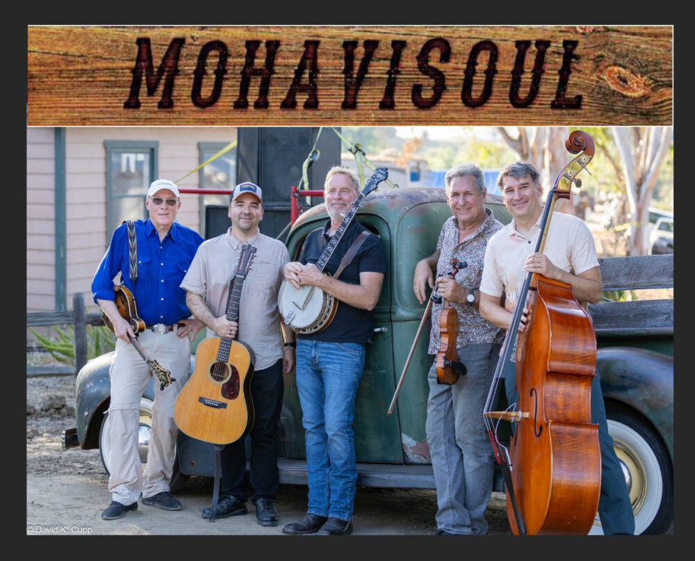 Five men with musical instruments stand in front of a vintage truck. A banner above them reads "MohaviSoul." The instruments include guitars, a banjo, a fiddle, and a double bass.