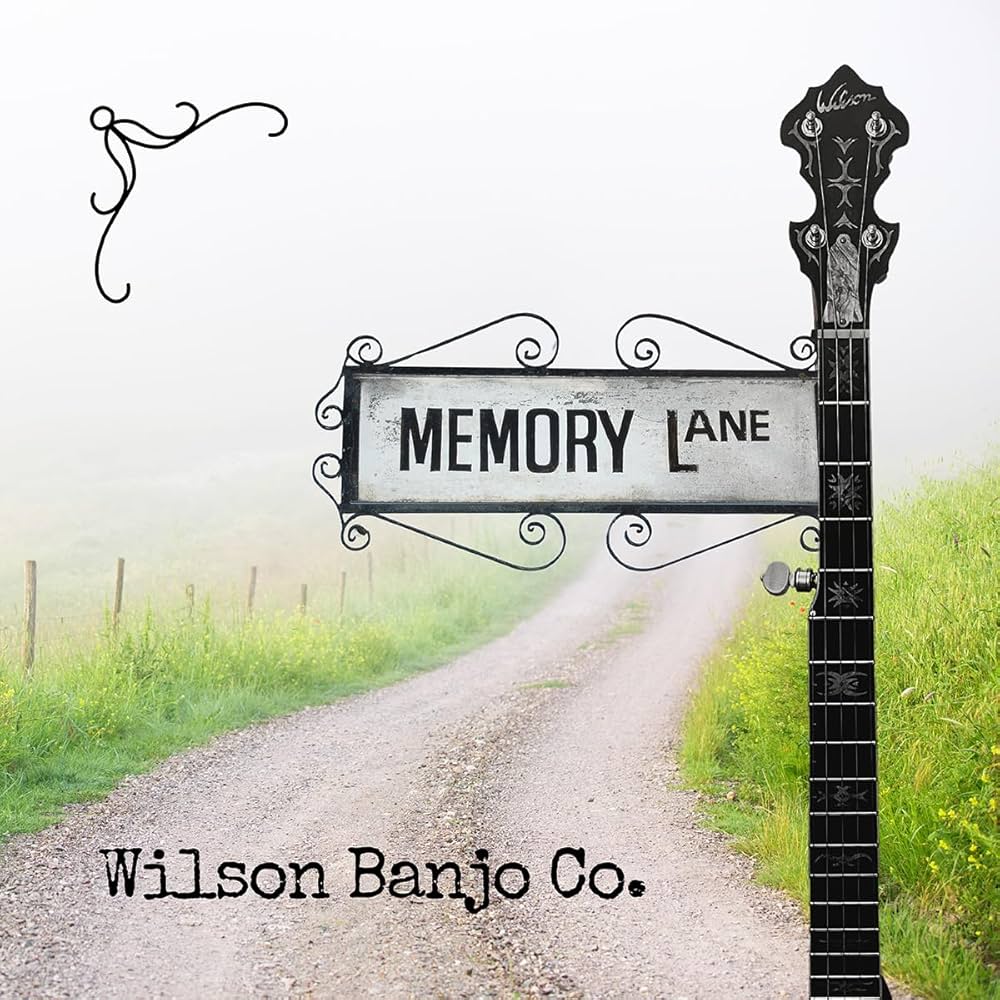 A gravel road leads off into fog with a street sign reading "Memory Lane" attached to a banjo neck. Text at the bottom reads "Wilson Banjo Co.