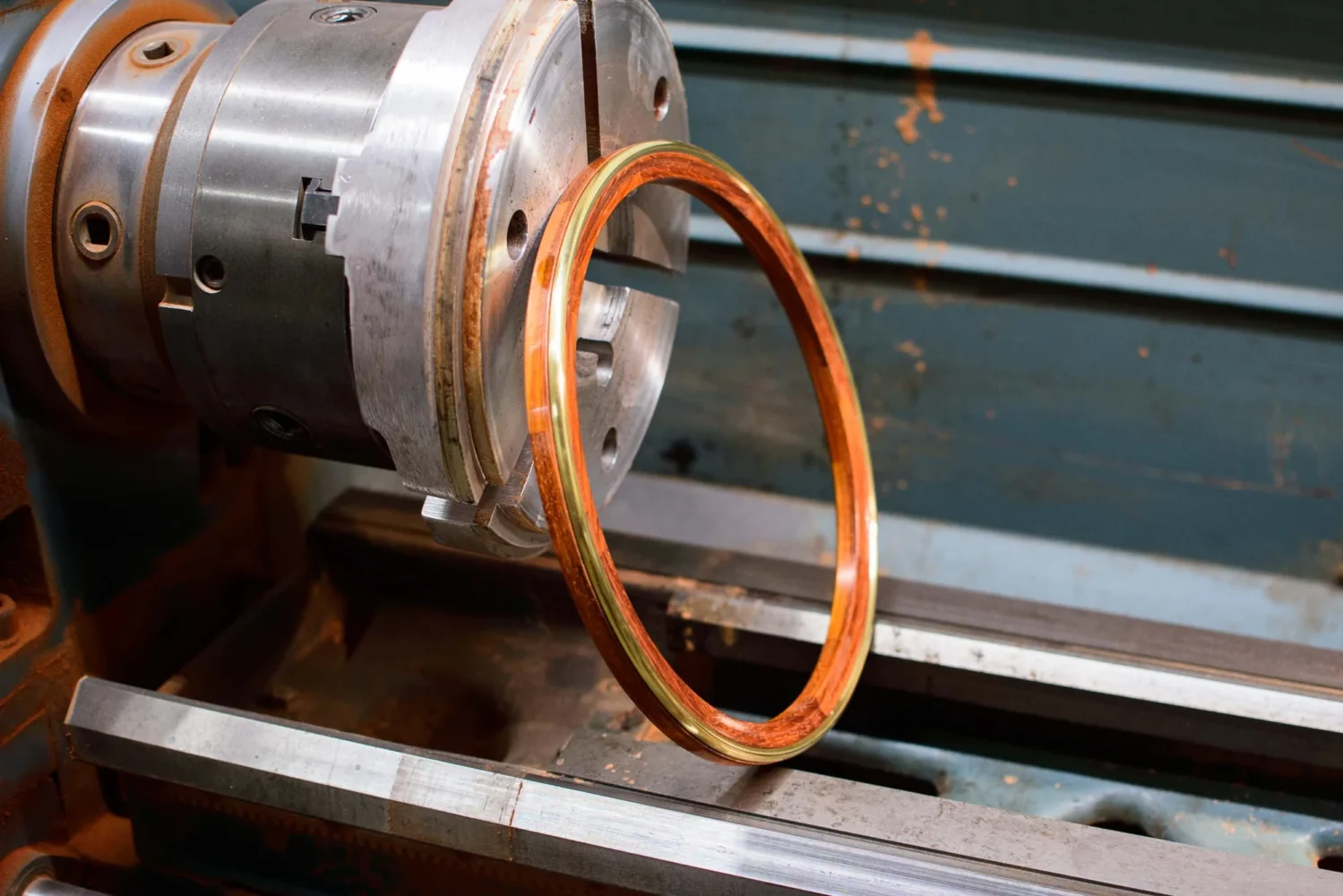A metal lathe holds a circular copper ring in its chuck, with machining marks visible on the metal surfaces.