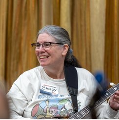 A woman with gray hair and glasses, wearing a name tag that says 