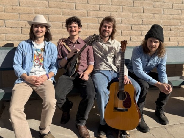 Faultliner Full Band cropped Four men sit on a bench outdoors with a brick wall behind them; one holds a mandolin and another rests his hand on an acoustic guitar.